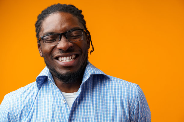 英俊微笑的年轻非洲男子孤立地站在橙色背景图片下载