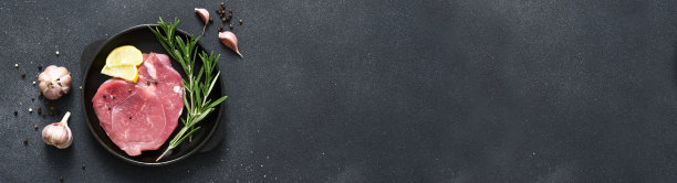 铸铁锅里的鲜肉，黑色背景上的生猪肉和香料图片下载