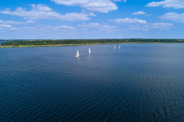 在一个阳光明媚的日子里，从空中俯瞰草原河上的帆船。在河上进行帆船运动。图片下载