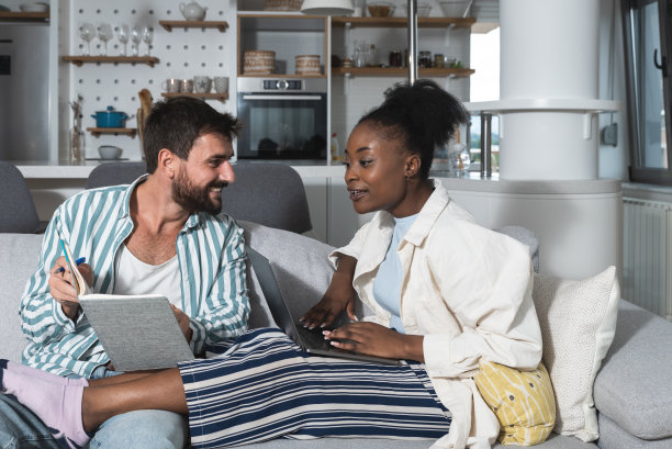 年轻夫妇，小企业主，在家工作。已婚的男人和女人坐在公寓的沙发上为他们自己的网站和公司设计新的商业理念和策略。图片下载