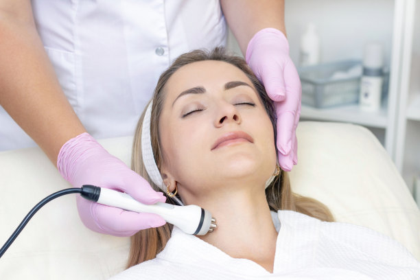 硬件美容。近距离图片可爱的年轻女子与闭着眼睛接受射频提升程序在美容院。图片下载