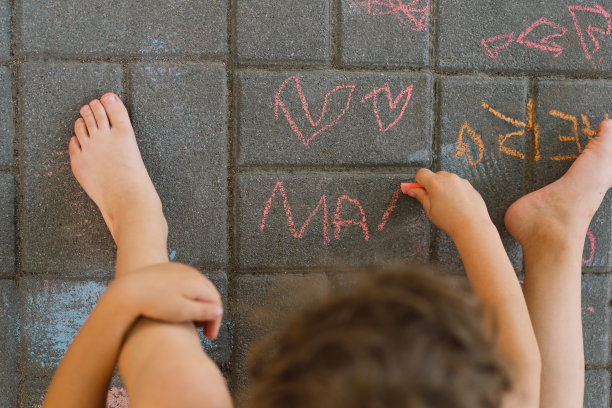 可爱的男孩用粉笔画出“妈妈”这个词。这个男孩爱他的母亲。图片下载