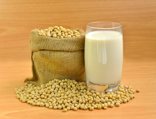 一瓶新鲜的豆浆和大豆隔离在木质纹理的背景上图片下载