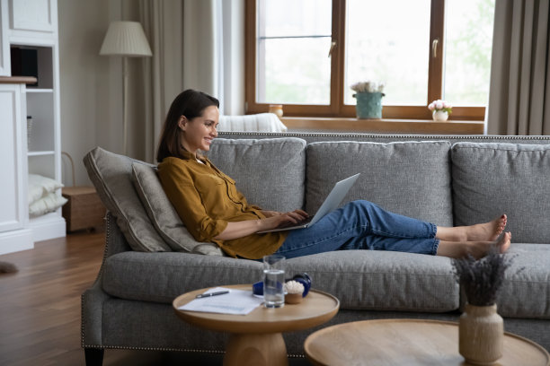 侧视女子坐在沙发上用笔记本电脑发短信图片下载