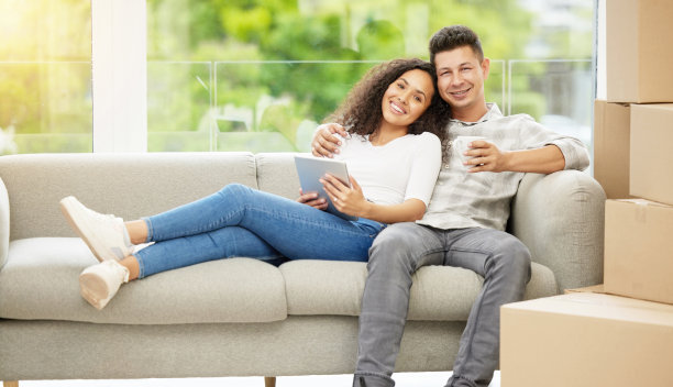 这张照片拍摄的是一对年轻夫妇在沙发上用数码平板电脑聊天图片下载