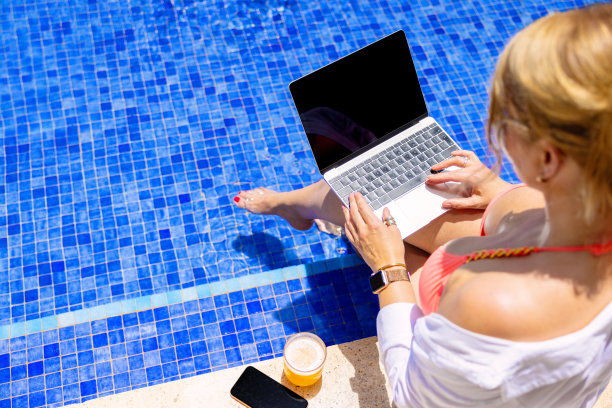 在泳池边用笔记本电脑工作的女人图片下载