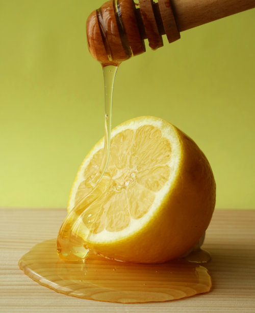 切好的柠檬和甜的蜂蜜放在木盘上图片下载