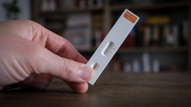 在家中，一只手拿冠状病毒检测呈阳性的特写照片图片下载