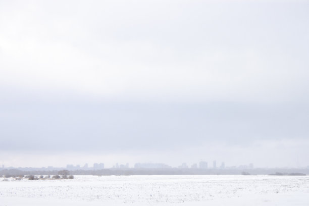 城市在远处的雾中。一个多云的蓝天在顶部和白色的雪在底部的框架。宽的风景照图片下载