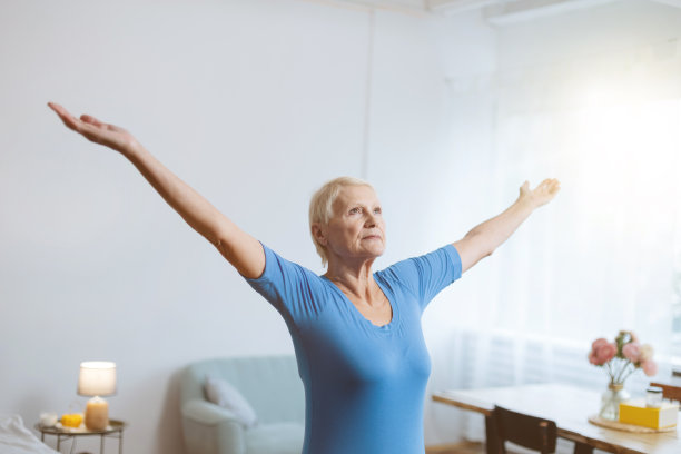 一位老妇人坐在一台打开的笔记本电脑前做瑜伽图片下载