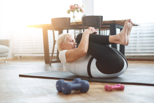 一位老妇人坐在一台打开的笔记本电脑前做瑜伽图片下载