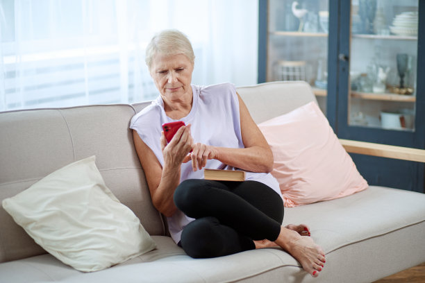 一位老妇人坐在一台打开的笔记本电脑前做瑜伽图片下载