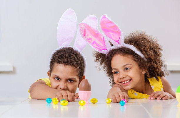 一个黑人女孩和一个男孩笑容满面地玩着复活节彩蛋图片下载