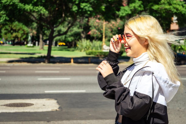 年轻漂亮的拉丁女郎穿着白衬衫穿过马路。图片下载