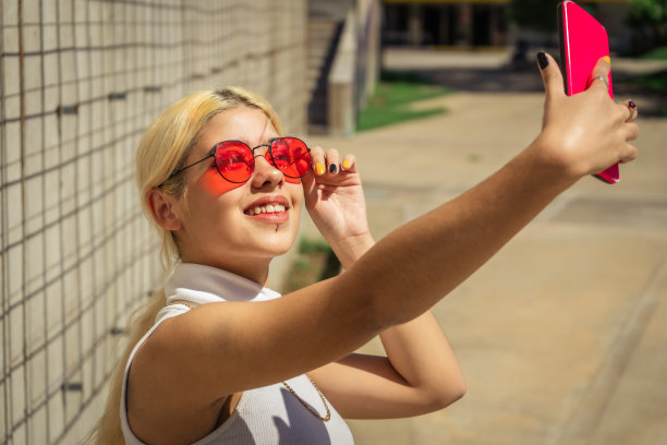 美丽的年轻拉丁女性在公共场所用她的手机自拍的图像。科技的概念，欢乐的概念图片下载