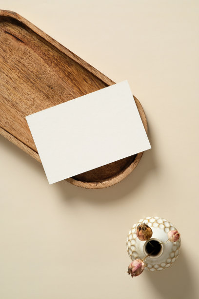 空白纸卡片模型在木制托盘上与花瓶在米色背景上的干花。平躺，顶视图，复制空间。图片下载