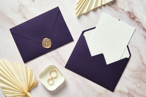 紫色的结婚信封，空白的卡片，金戒指，干花在大理石桌子上。图片下载
