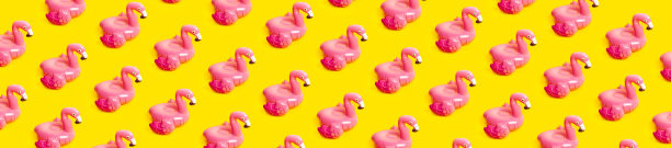 创意夏日海滩概念。图案从充气粉红色迷你火烈鸟黄色背景，泳池浮子派对。平铺，复制空间。火烈鸟充气玩具。夏天的背景图片下载