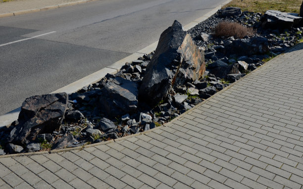在街道上的停车场内，由路肩包围的砾石铺装区域。各种大小的粗石料。没有植物的深灰色岩石花园图片下载
