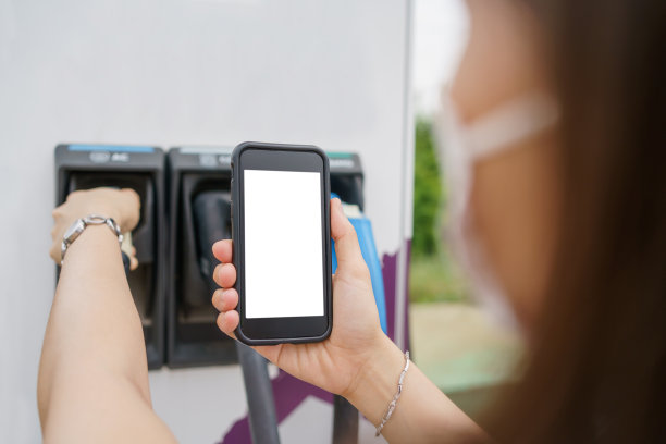 女子用智能手机连接电动汽车充电站。图片下载