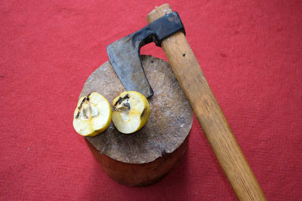 用斧子切木瓜。所有的都停留在红地毯背景的木头上。图片下载