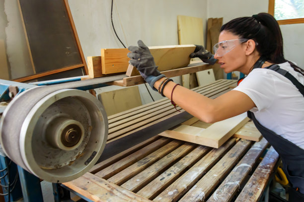 木匠女工在木工车间使用砂光机。图片下载