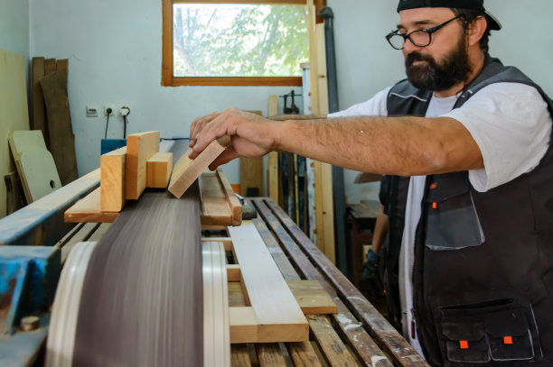 一个男木匠在车间里使用磨砂机。图片下载