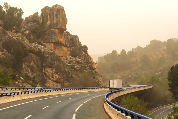 冷藏车在峡谷的高架桥上穿行，这是一个雾蒙蒙的日子。图片下载