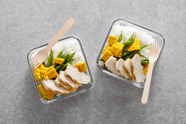 配有烤鸡胸肉、米饭、玉米和青豆的午餐盒。俯视图，平躺图片下载