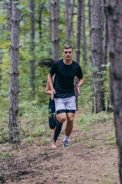 一个有吸引力的男性运动员在森林中奔跑的全长照片图片下载