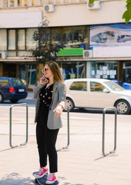 女商人一边打手机一边玩滑板图片下载