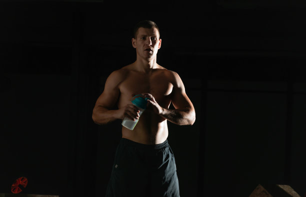 年轻英俊的健美运动员喝着瓶子里的水，正从锻炼中休息图片下载