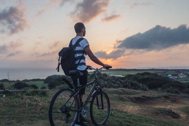 年轻人傍晚骑着自行车，欣赏着大自然图片下载