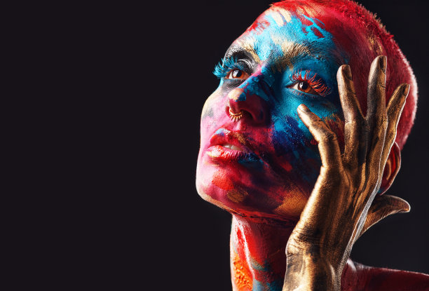 这张照片是一个迷人的年轻女子独自在画室里摆姿势，脸上涂着颜料图片下载