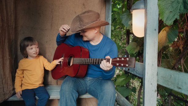 牛仔爸爸为他的小孩弹奏原声吉他。旧的,复古的装饰图片下载