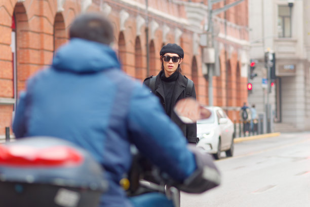 帅气的中国年轻男子身穿黑色大衣，毛衣和裤子，戴着太阳镜走在上海的街道上，正面，男性时尚，酷的亚洲年轻人的生活方式的肖像。图片下载