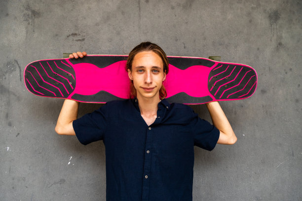 白人少年拿着长板看着镜头。本空间图片下载