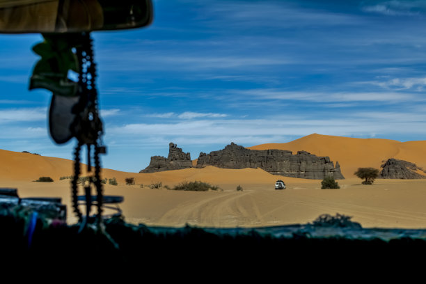 从车里的挡风玻璃上看到的沙丘、岩石嶙峋的沙漠山脉图片下载