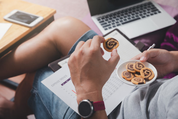 一个穿着便服的男人在他的家庭办公室工作的时候捡饼干。图片下载