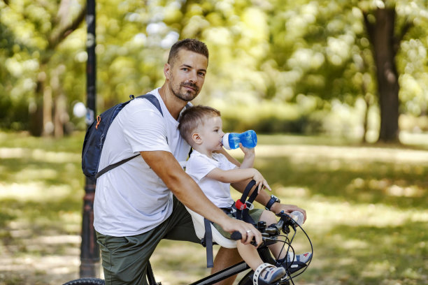 有保护欲的父亲在和口渴的儿子骑车休息。图片下载