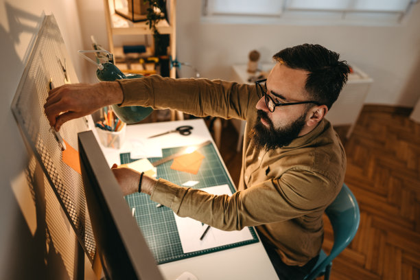大胡子艺术家在车间的小钉板上贴橘色的贴纸图片下载