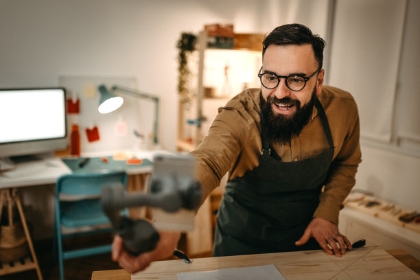 留着胡子的艺术家在工作室用智能手机做视频指导图片下载