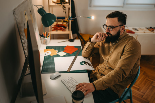 留着胡子的男性艺术家在工作室里用电脑工作图片下载