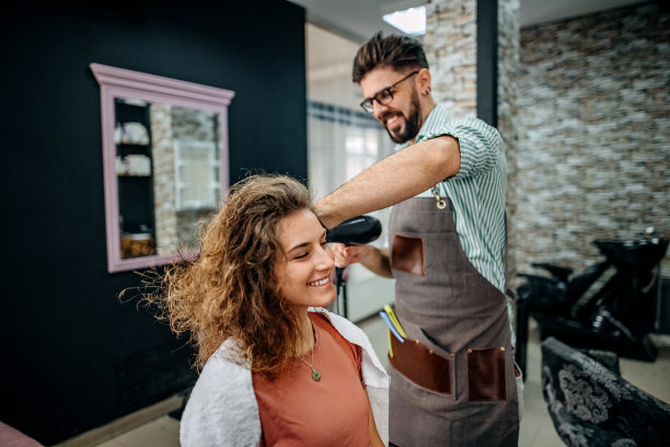 发型师正在为妇女干头发图片下载
