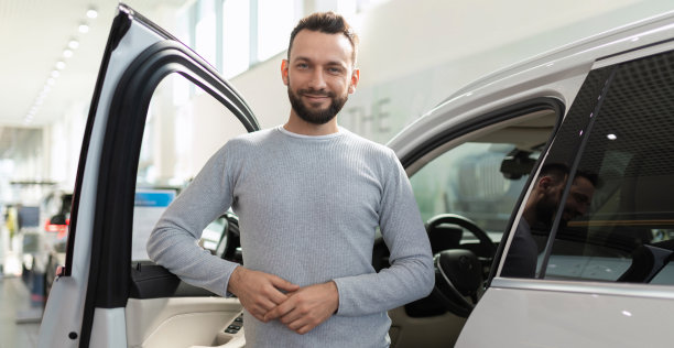 新购车者在suv旁边的汽车展厅里很开心图片下载