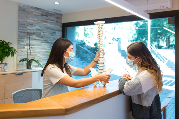 女理疗师在会诊期间向病人解释脊柱模型。图片下载
