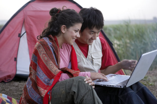 年轻情侣在户外使用笔记本电脑图片下载