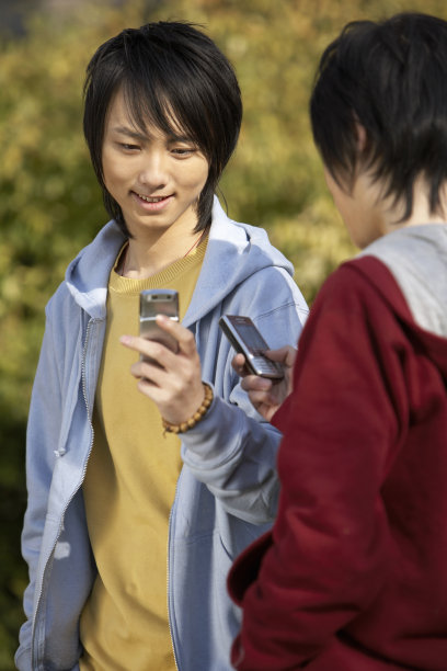 2个把玩手机的年轻男孩图片下载