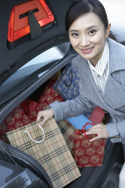 商务女性从汽车后备箱里取出许多购物袋图片下载