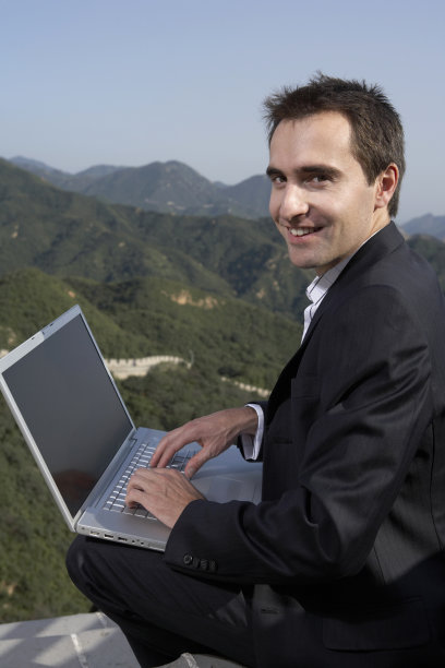 商务男士在长城上使用笔记本电脑图片下载